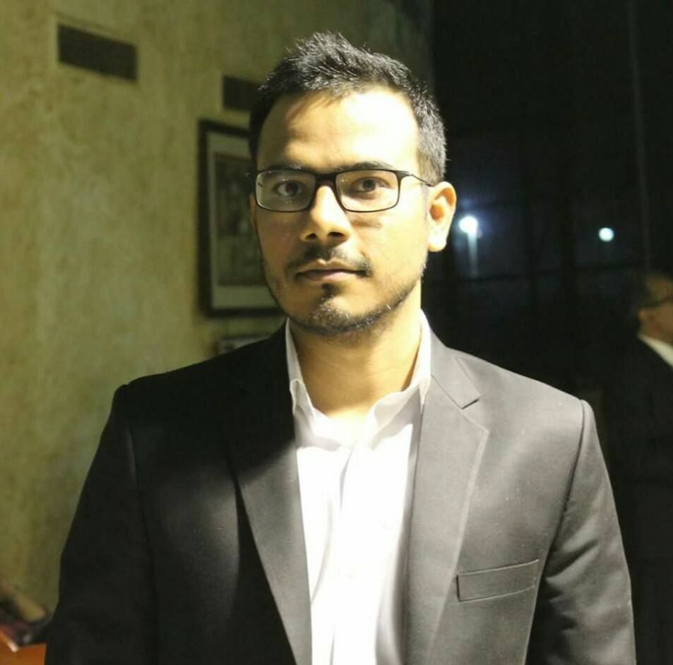 Diwakar in a dark suit and glasses